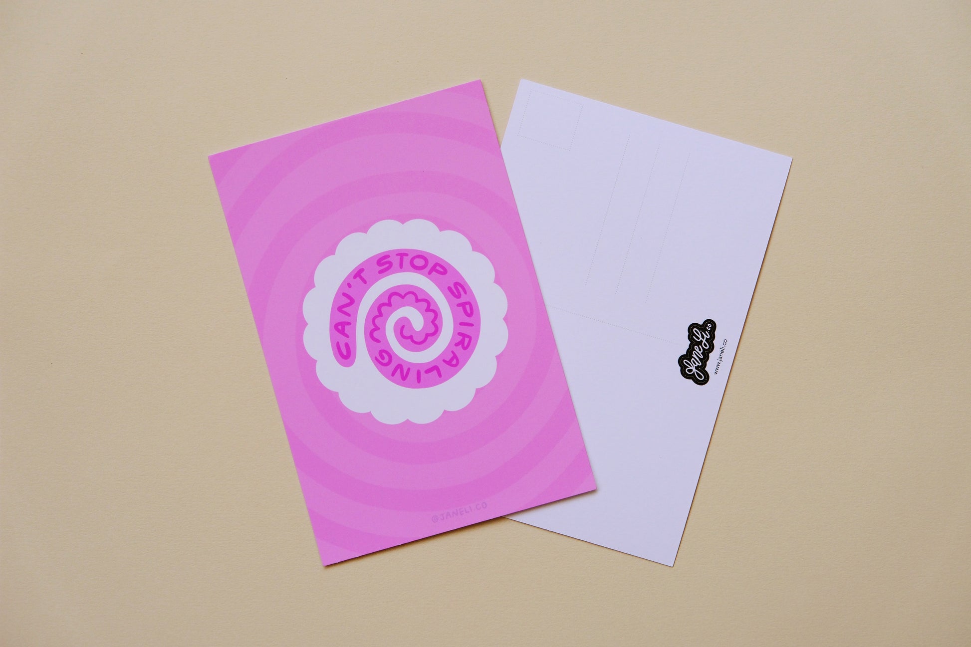 A JaneLi.Co mini print/postcard of a white fish cake with a pink spiral that says "Can't stop spiraling" and a back postcard side of the same print over a pink background.