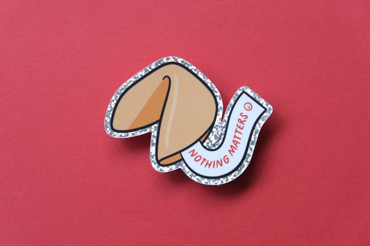 A JaneLi.Co sticker of a fortune cookie that says "Nothing Matters" over a red background.