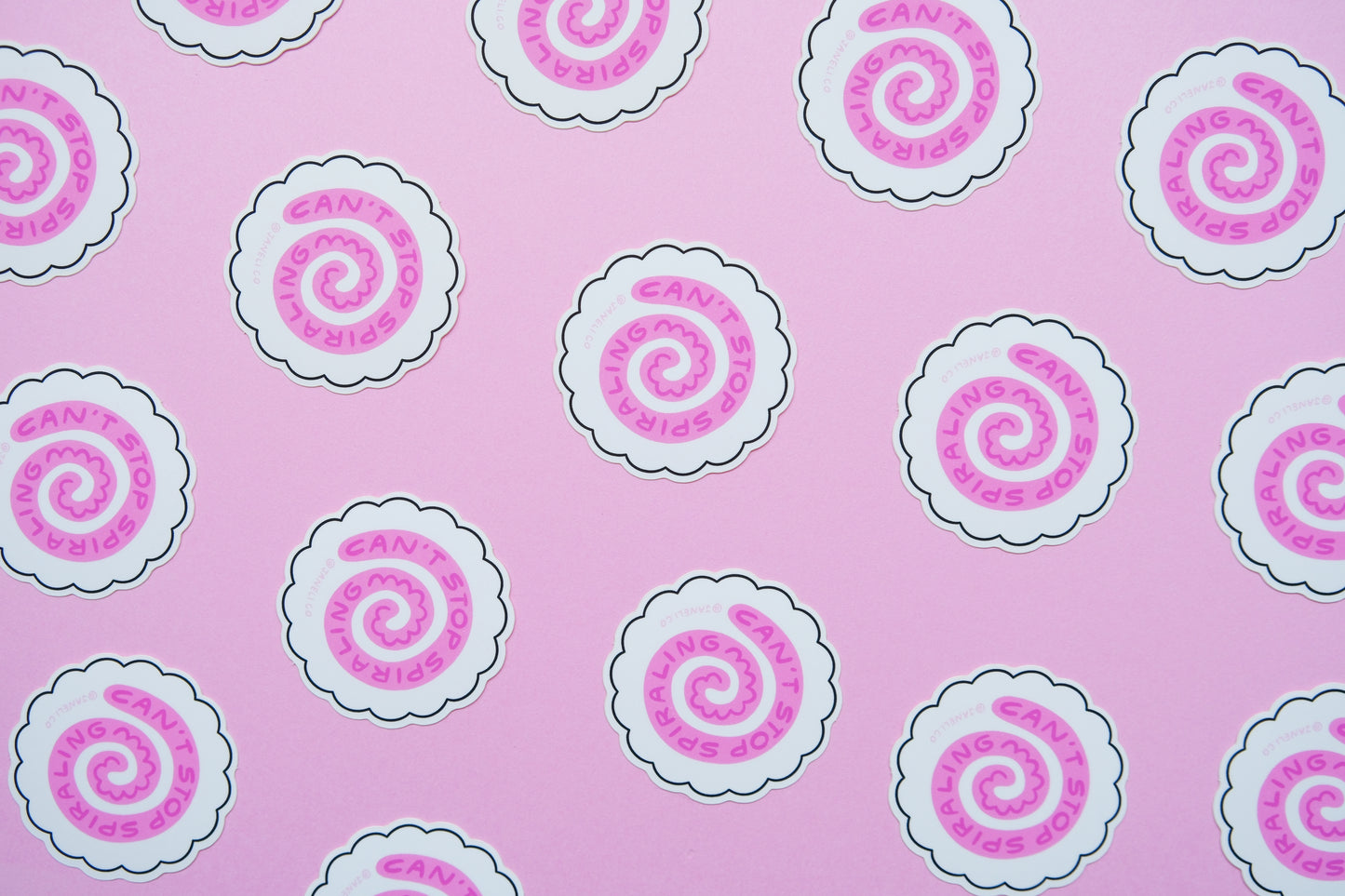A grid of JaneLi.Co stickers of white fish cakes with pink swirls that say "Can't stop spiraling" over a pink background.