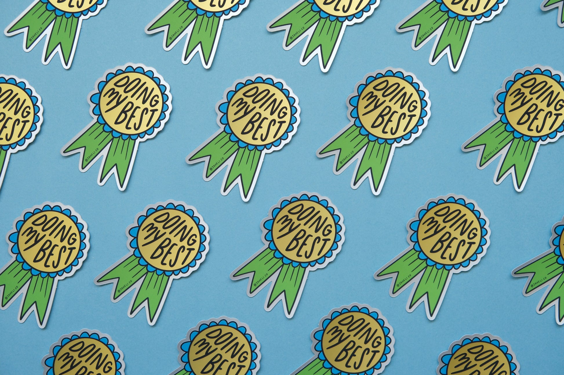 A grid of JaneLi.Co stickers of blue and green award ribbons that say "Doing My Best" over a blue background.