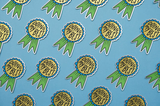 A grid of JaneLi.Co stickers of blue and green award ribbons that say "Doing My Best" over a blue background.