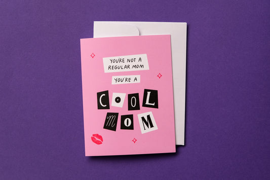 A photo of a greeting card with scrapbook cutout letters that say "You're not a regular mom you're a cool mom" and a white envelope on a purple background.