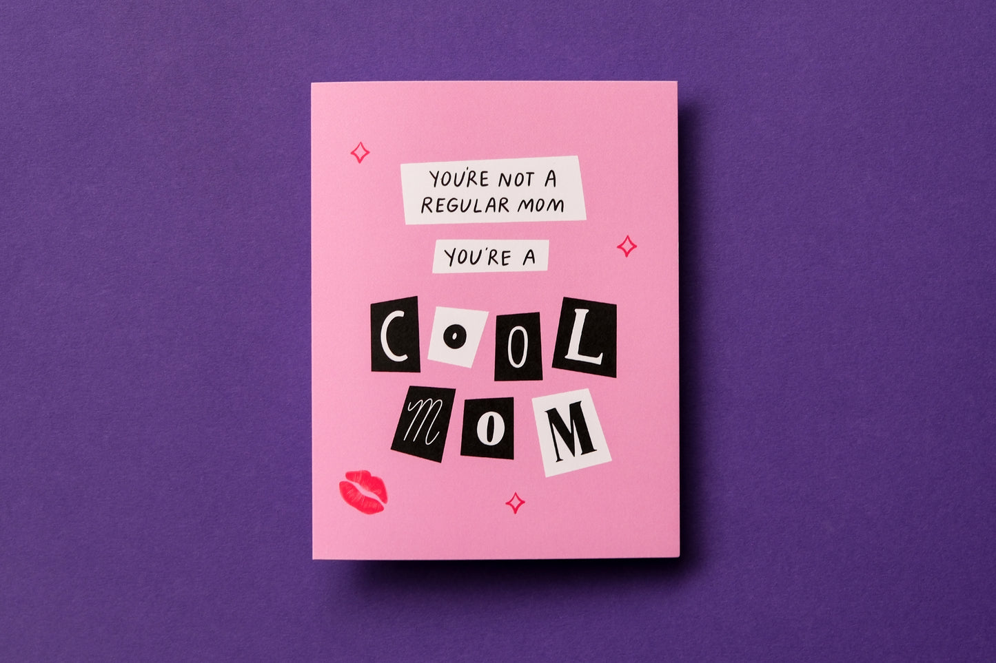A photo of a greeting card with scrapbook cutout letters that say "You're not a regular mom you're a cool mom" on a purple background.