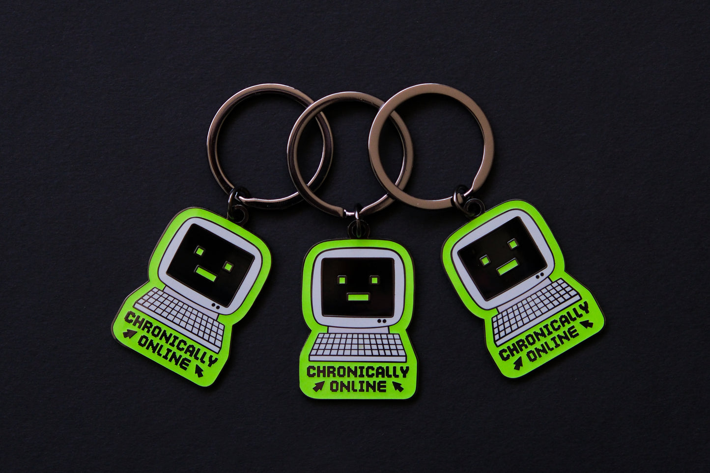 3 enamel keychains of retro computers that say "Chronically Online" over a black background.