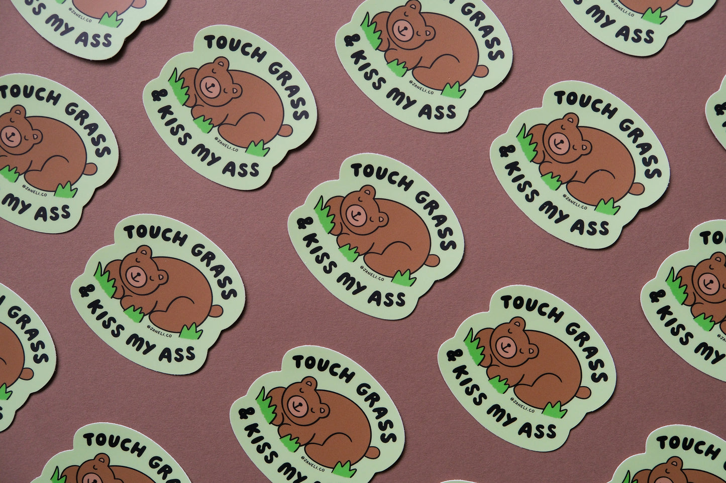 A grid of JaneLi.Co stickers of napping brown bears that say "Touch grass and kiss my ass" over a brown background.