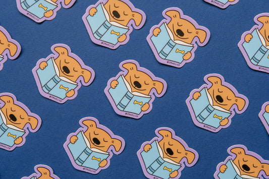 A grid of JaneLi.Co stickers of dogs reading books over a dark blue background.