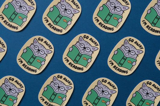 A grid of JaneLi.Co stickers of cats reading books that say "Go Away I'm Reading" over a teal background.