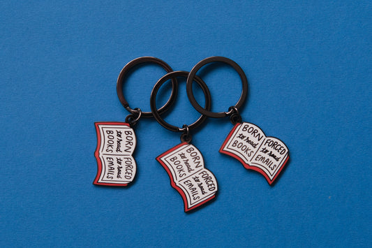3 enamel keychains of open books that say "Born to read books, Forced to read emails" over a blue background.