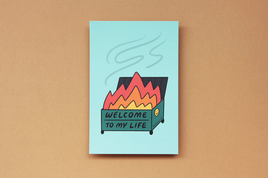 A JaneLi.Co mini print/postcard of a dumpster fire that says "Welcome to My Life" over a tan background.