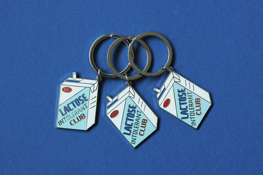 3 enamel keychains showing a soymilk carton that says" Lactose Intolerant Club" over a blue background.