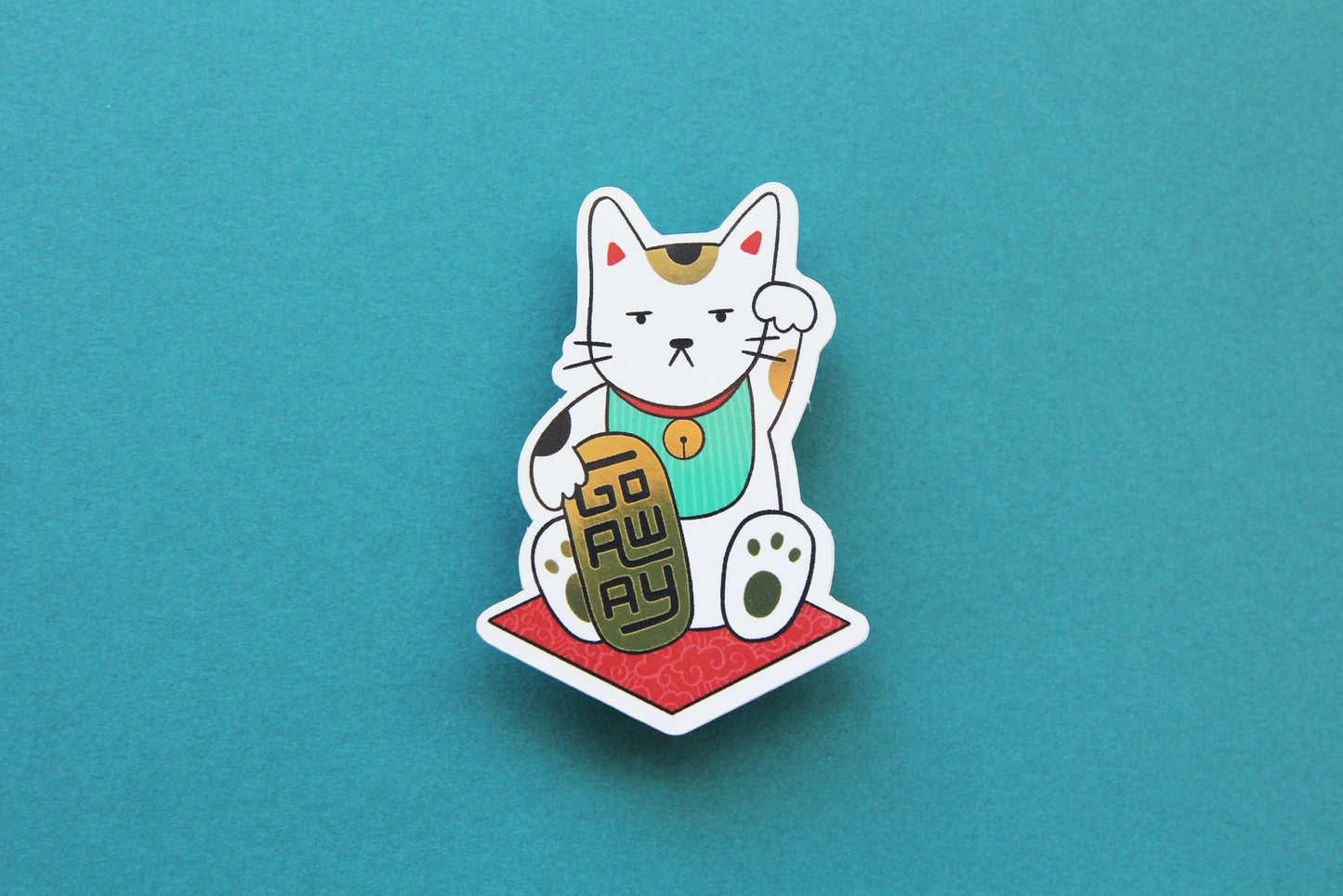 A JaneLi.Co sticker that shows a Maneki Neko cat holding a metallic gold bar that says "Go Away" over a teal background.