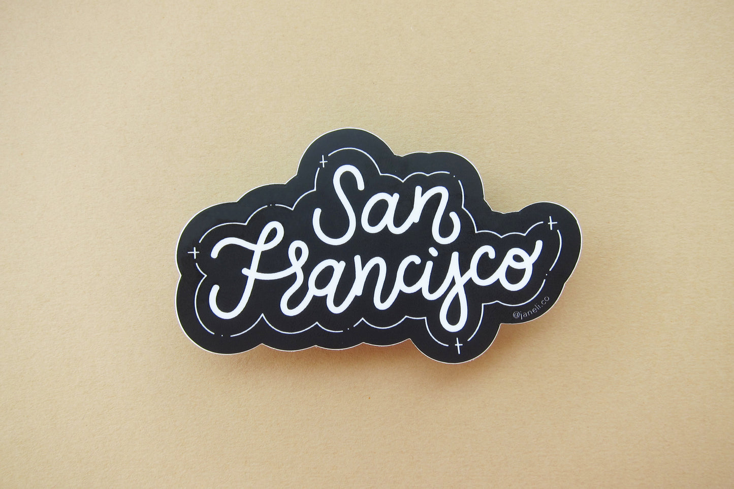 A black and white JaneLi.Co sticker that says "San Francisco" in cursive lettering over a tan background.