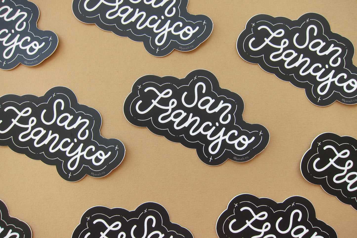 A grid of black and white JaneLi.Co stickers that say "San Francisco" in cursive lettering over a tan background.