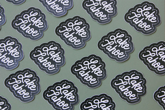 A grid of black and white JaneLi.Co stickers that say "Lake Tahoe" in cursive lettering over a green background.
