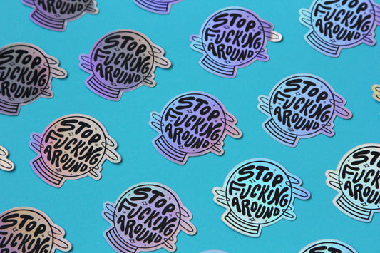 A grid of holographic JaneLi.Co stickers that say "Stop Fucking Around" in a magic crystal ball over a blue background.