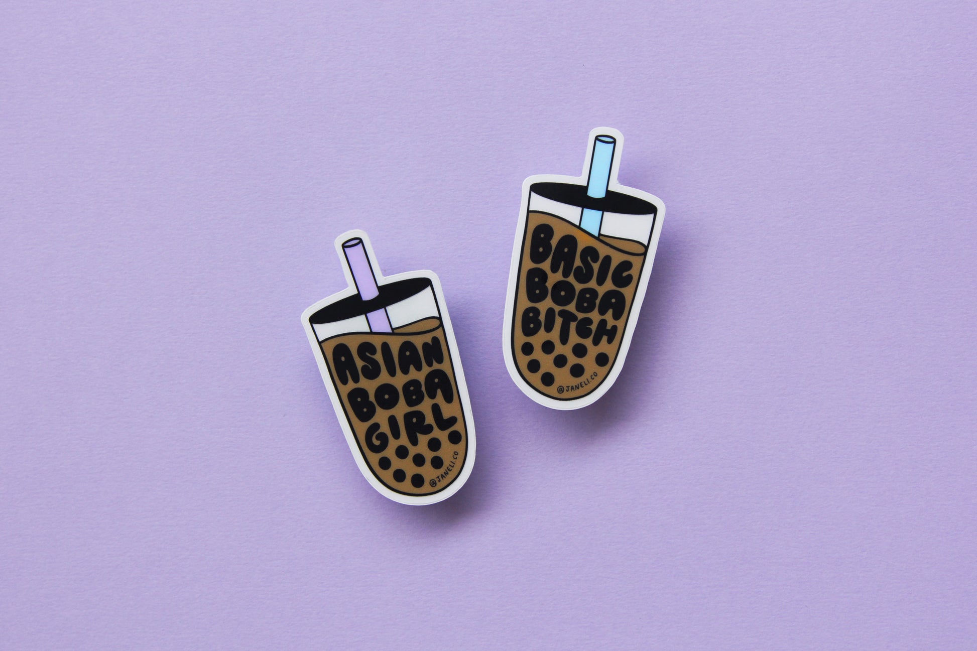 Two JaneLi.Co stickers in the shape of cups of boba over a lavender background. One of the cups says "Asian Boba Girl" with a purple straw, and the other says "Basic Boba Bitch" with a blue straw.