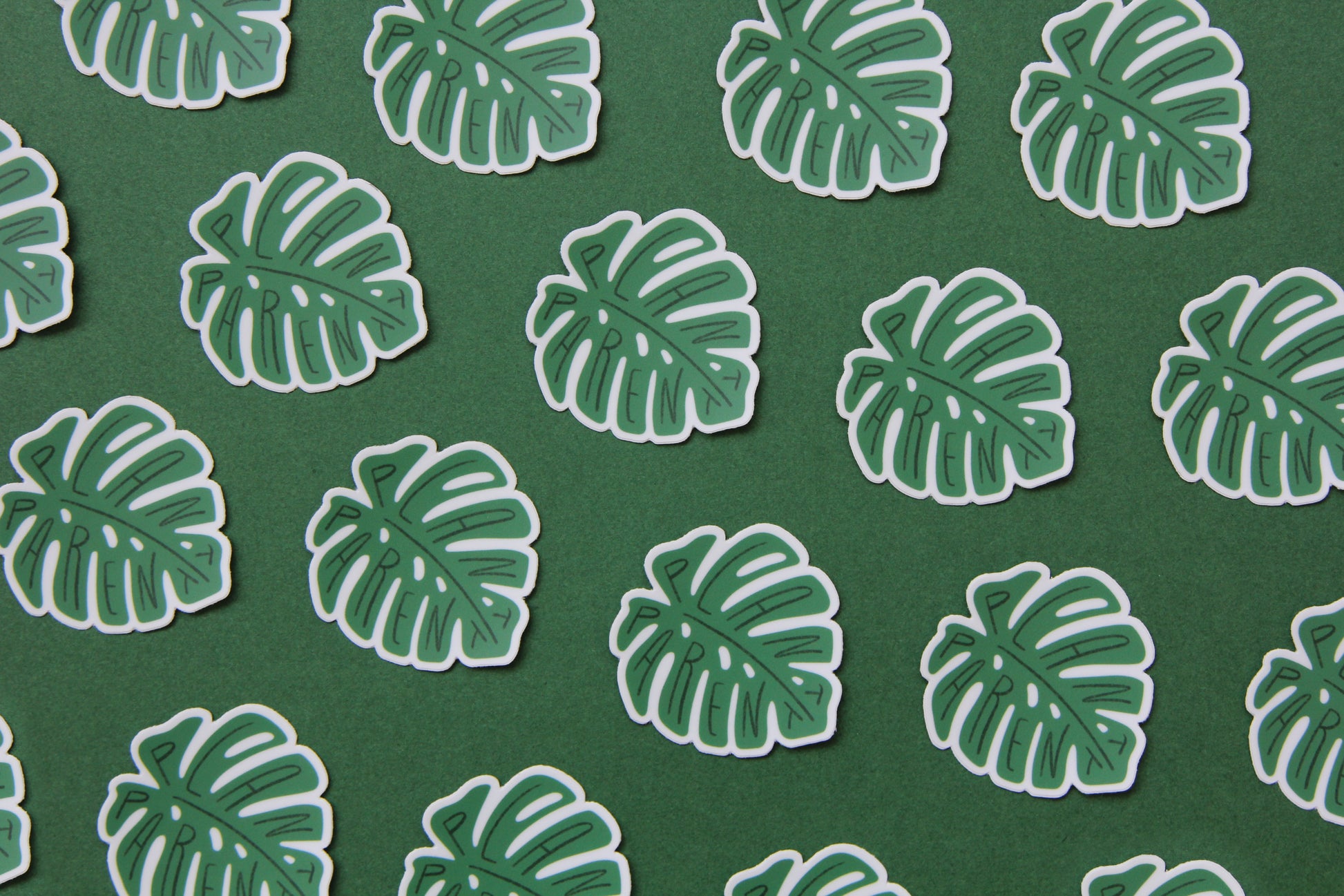 A grid of green JaneLi.Co stickers that say "Plant Parent" in the shape of monstera leaves over a green background.
