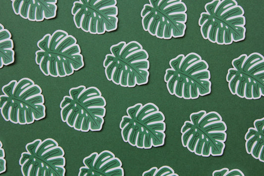 A grid of green JaneLi.Co stickers that say "Plant Parent" in the shape of monstera leaves over a green background.