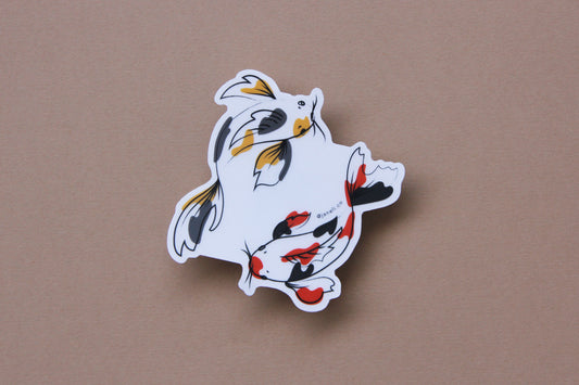 A JaneLi.Co sticker of a gold and grey koi fish and a scarlet and black koi fish swimming in a circle over a tan background.