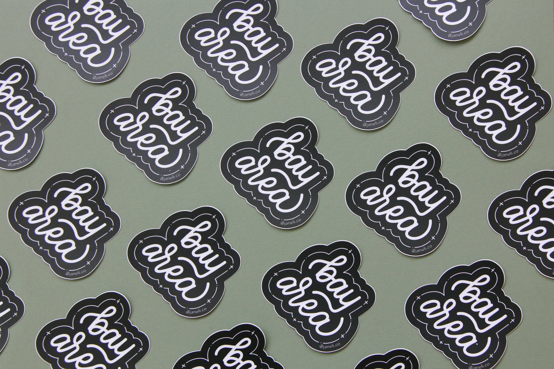 A grid of black and white JaneLi.Co stickers that say "Bay Area" in cursive lettering over a green background.