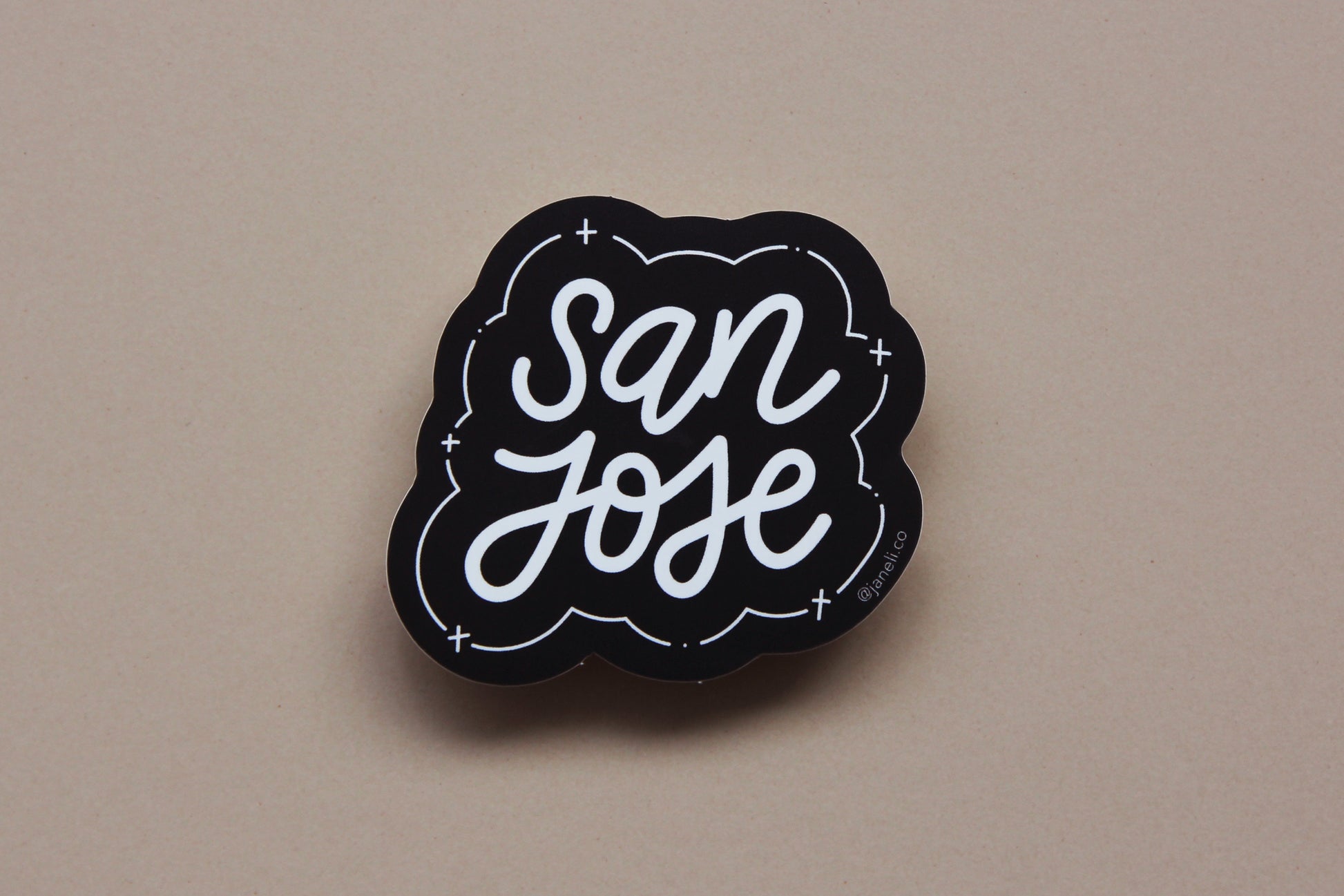 A black and white JaneLi.Co sticker that says "San Jose" in cursive lettering over a tan background.