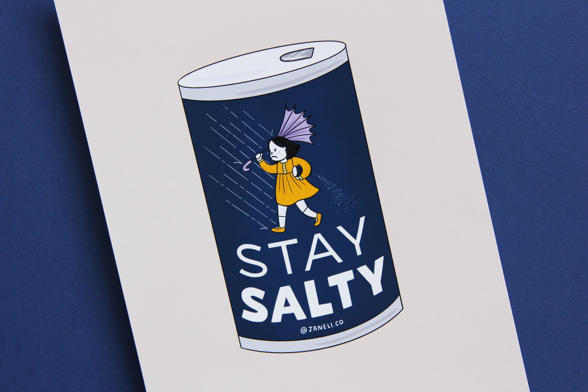 A close up of a JaneLi.Co print that shows a grumpy salt girl spilling a can of salt in the rain over a navy background.