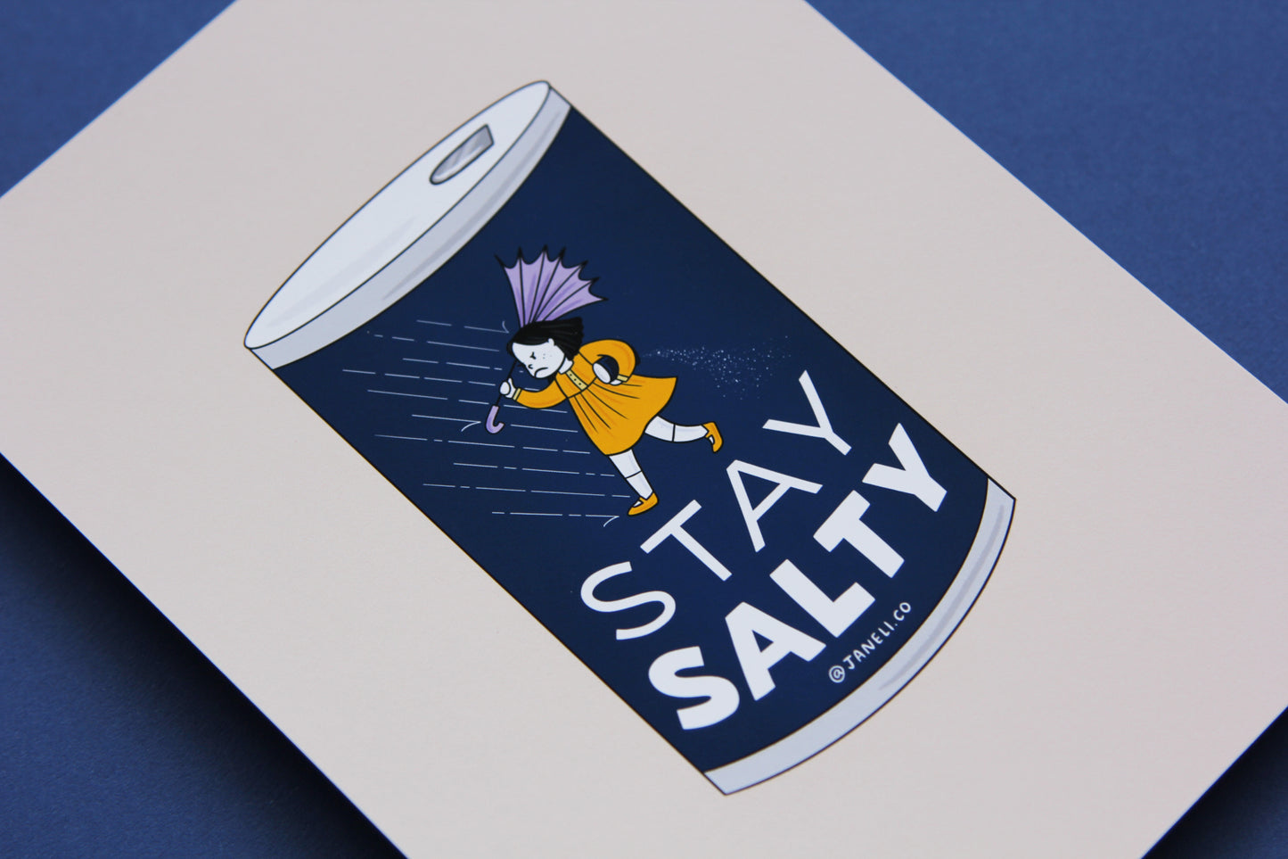 A close up of a JaneLi.Co print that shows a grumpy salt girl spilling a can of salt in the rain over a navy background.