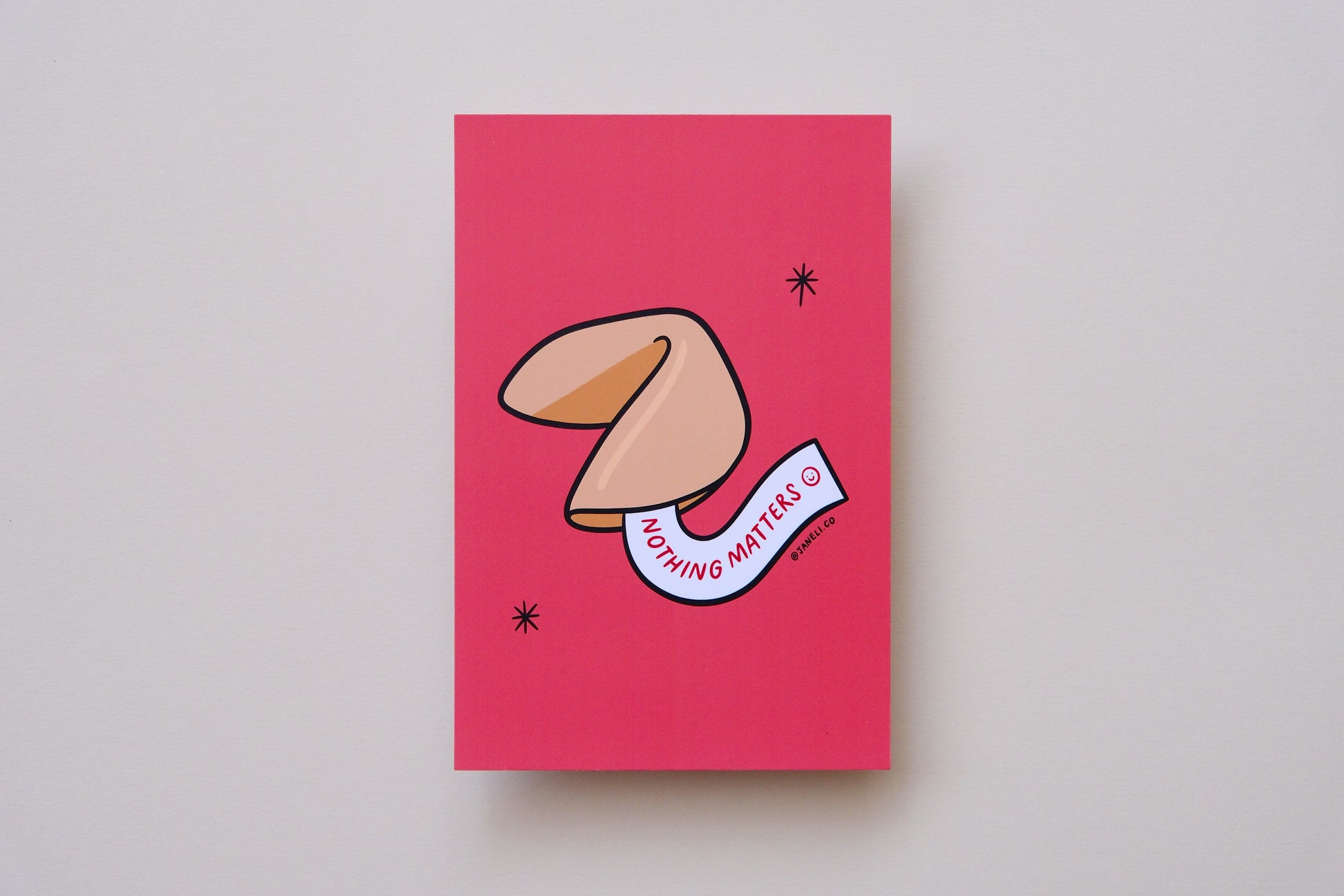 A JaneLi.Co mini print/postcard of a fortune cookie that says "Nothing Matters" over a cream background.