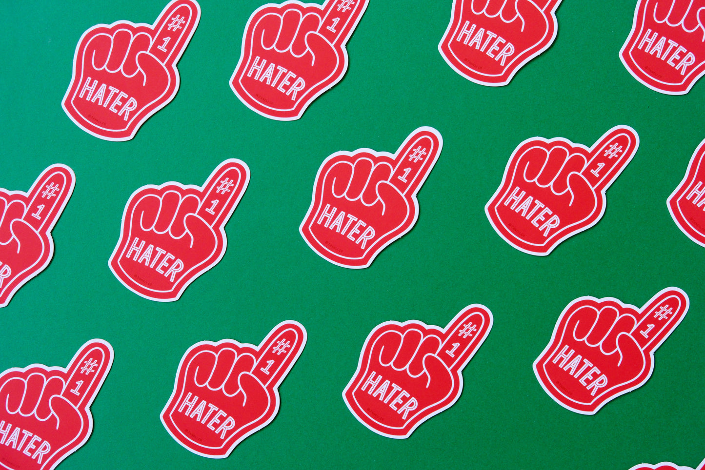 A grid of JaneLi.Co stickers of red foam fingers that say "#1 Hater" over a green background.