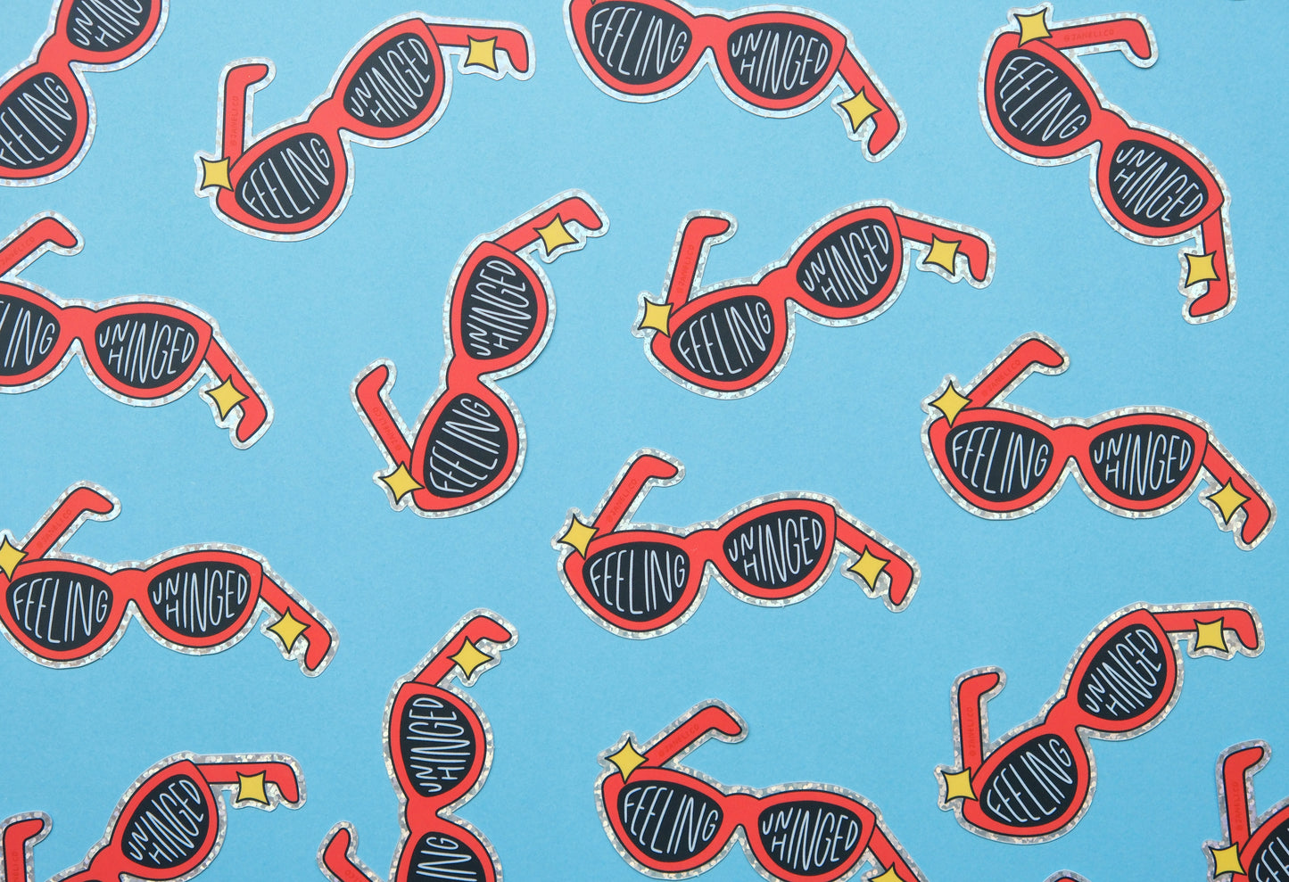   A grid of JaneLi.Co stickers of broken red sunglasses that say "Feeling Unhinged" over a blue background.