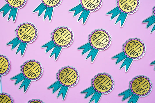 A grid of JaneLi.Co stickers of pink and teal award ribbons that say "Petty As Fuck" over a pink background.
