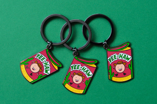 3 enamel keychains showing rolls of haw flakes that say "Yee-Haw" over a green background.