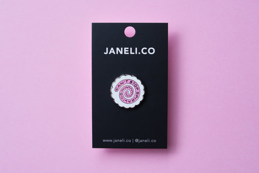 An enamel pin showing a narutomaki fishcake that says "Can't Stop Spiraling" on a black JaneLi.Co backing card over a pink background.
