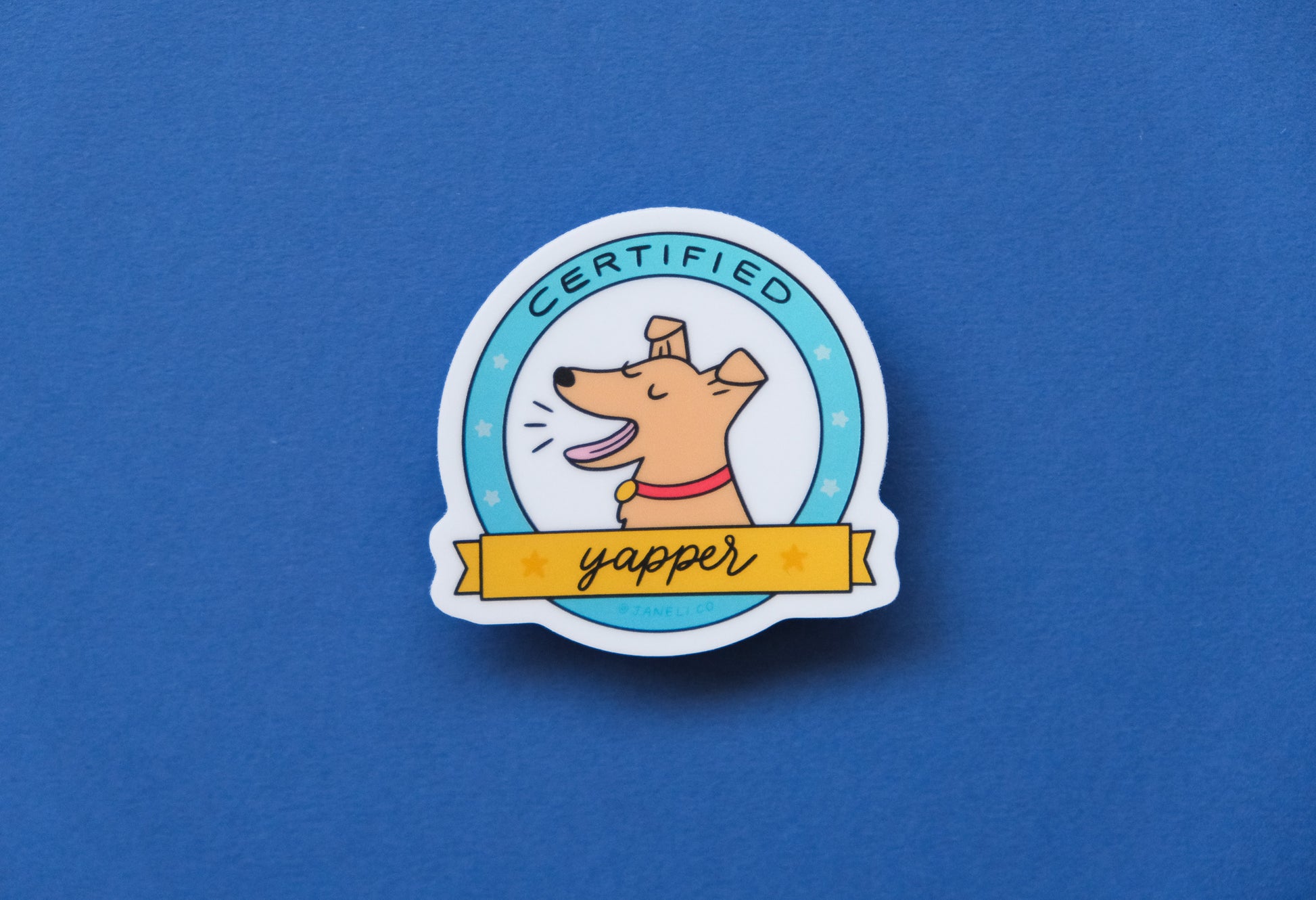 A JaneLi.Co sticker of a badge with a barking dog that says "Certified Yapper" over a blue background.