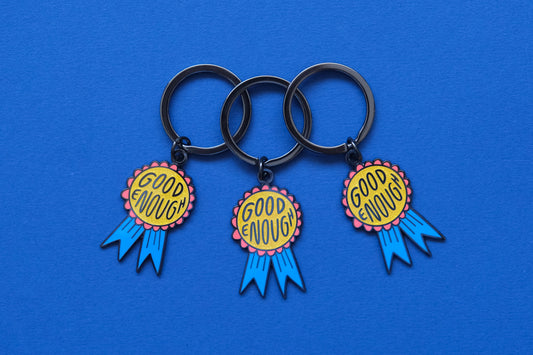 3 enamel keychains showing glittery red and blue award ribbons that says "Good Enough" over a blue background.