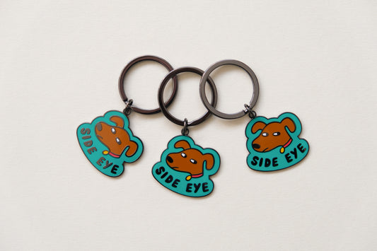 3 enamel keychains showing sassy dogs giving side eye that say "Side Eye" over a cream background.