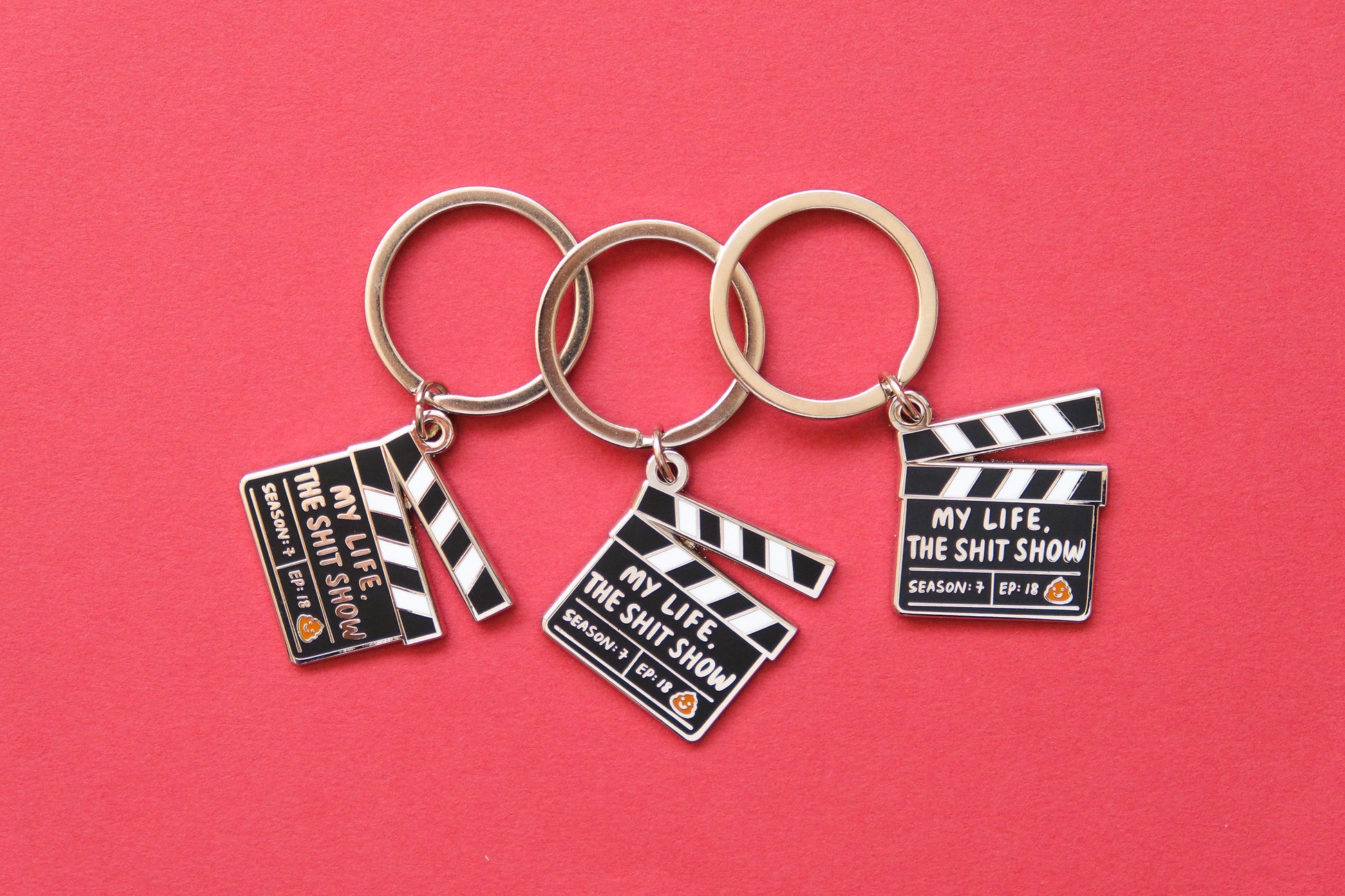 3 enamel keychains showing movie clappers that say "My Life, the Shit Show" over a red background.