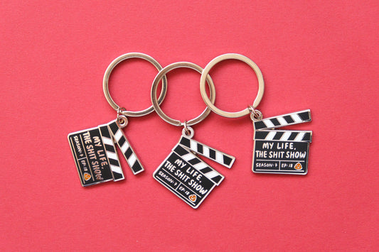 3 enamel keychains showing movie clappers that say "My Life, the Shit Show" over a red background.