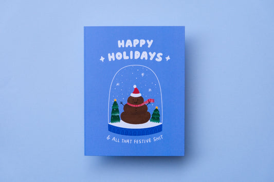 A photo of a greeting card that says "Happy holidays and all that festive shit" with a poop snowman in a snowglobe on a blue background.