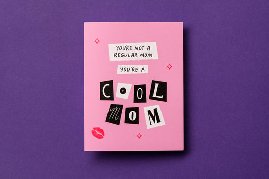 A photo of a greeting card with scrapbook cutout letters that say "You're not a regular mom you're a cool mom" on a purple background.