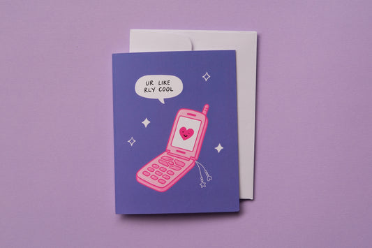 A photo of a greeting card that says "ur like rly cool" with a pink retro flip phone and a white envelope on a lavender background.