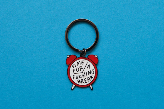 An enamel keychain of an alarm clock that says "Time for a Fucking Break" over a blue background.