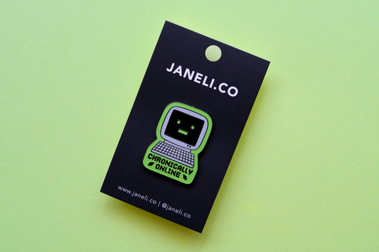 An enamel pin of a retro computer that says "Chronically Online" on a black JaneLi.Co backing card over a green background.