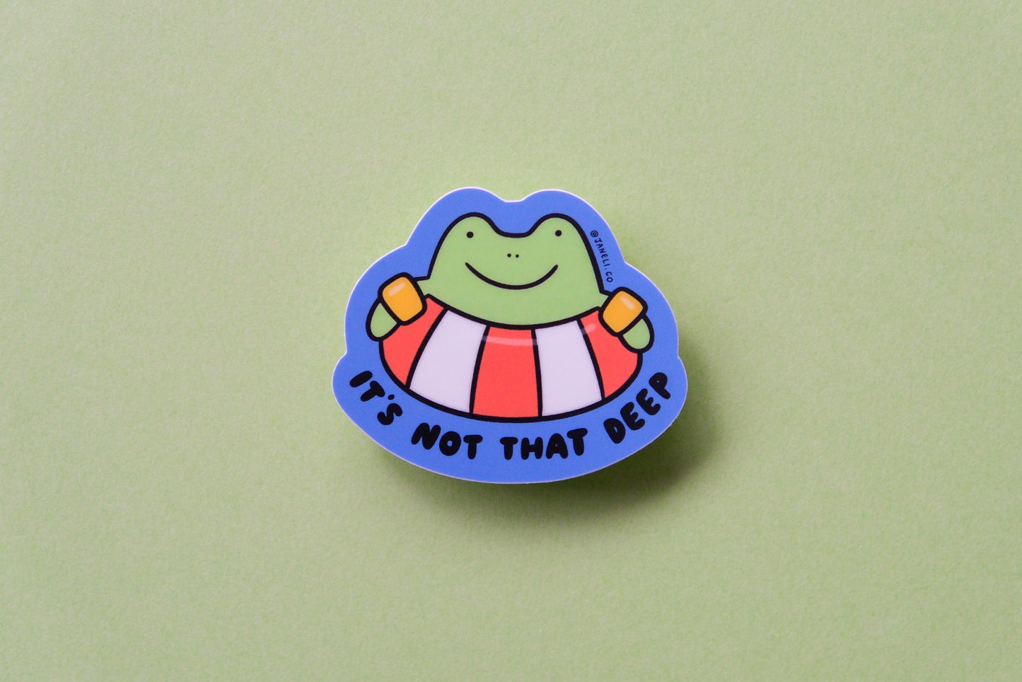 A JaneLi.Co sticker of a frog floating in a lifessaver tube that says "It's not that deep" over a green background.