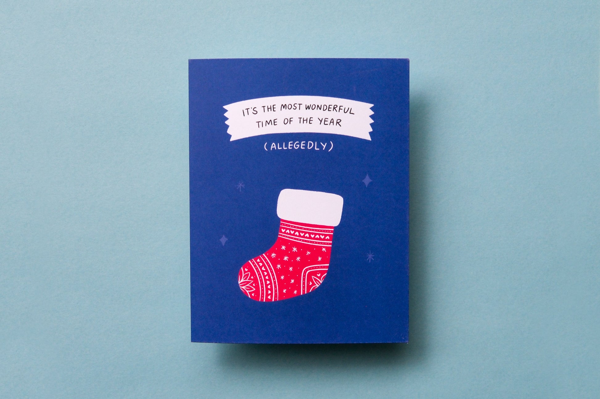 A photo of a greeting card with a stocking that says "It's the most wonderful time of the year (allegedly)" on a blue background.