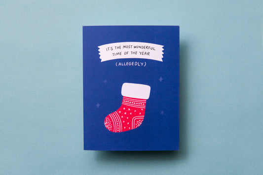A photo of a greeting card with a stocking that says "It's the most wonderful time of the year (allegedly)" on a blue background.