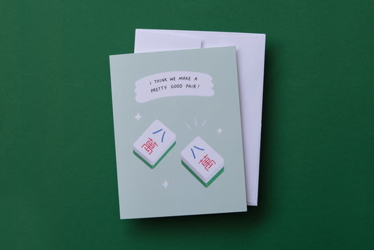 A photo of a greeting card with a pair of matching mahjong tiles "I think we make a pretty good pair!" on a green background.