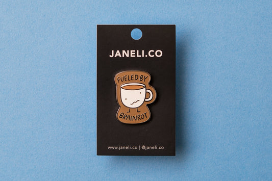 An enamel pin of a wonky coffee mug that says "Fueled by brainrot" over a blue background.