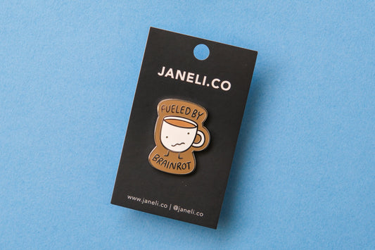 An enamel pin of a wonky coffee mug that says "Fueled by brainrot" over a blue background.