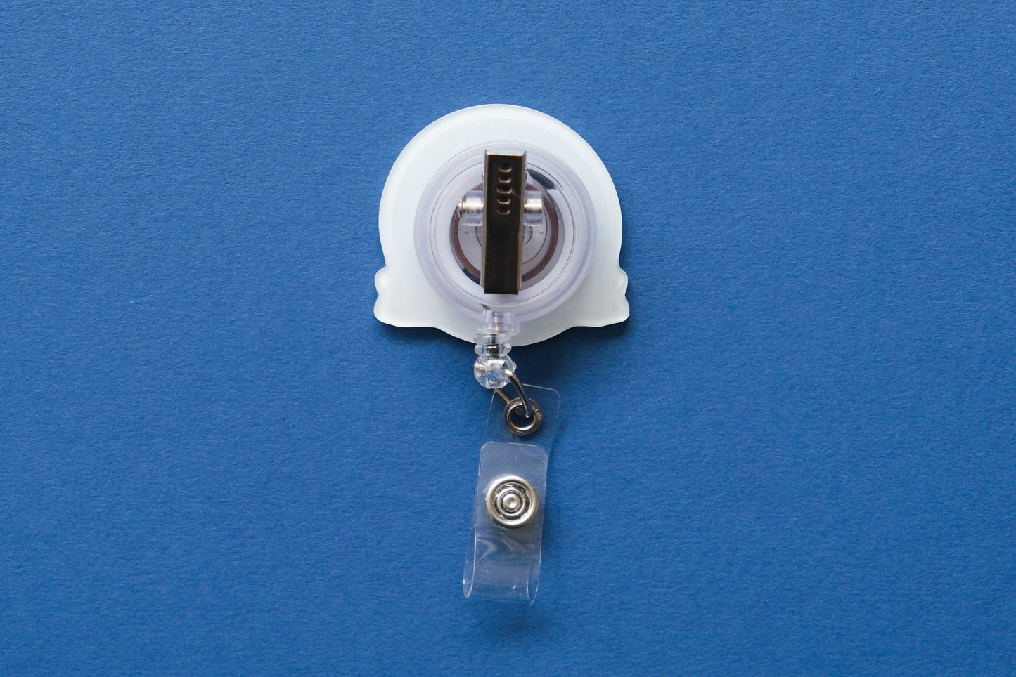A retractable badge reel with a clear plastic clip and a white acrylic badge, shown against a solid blue background.